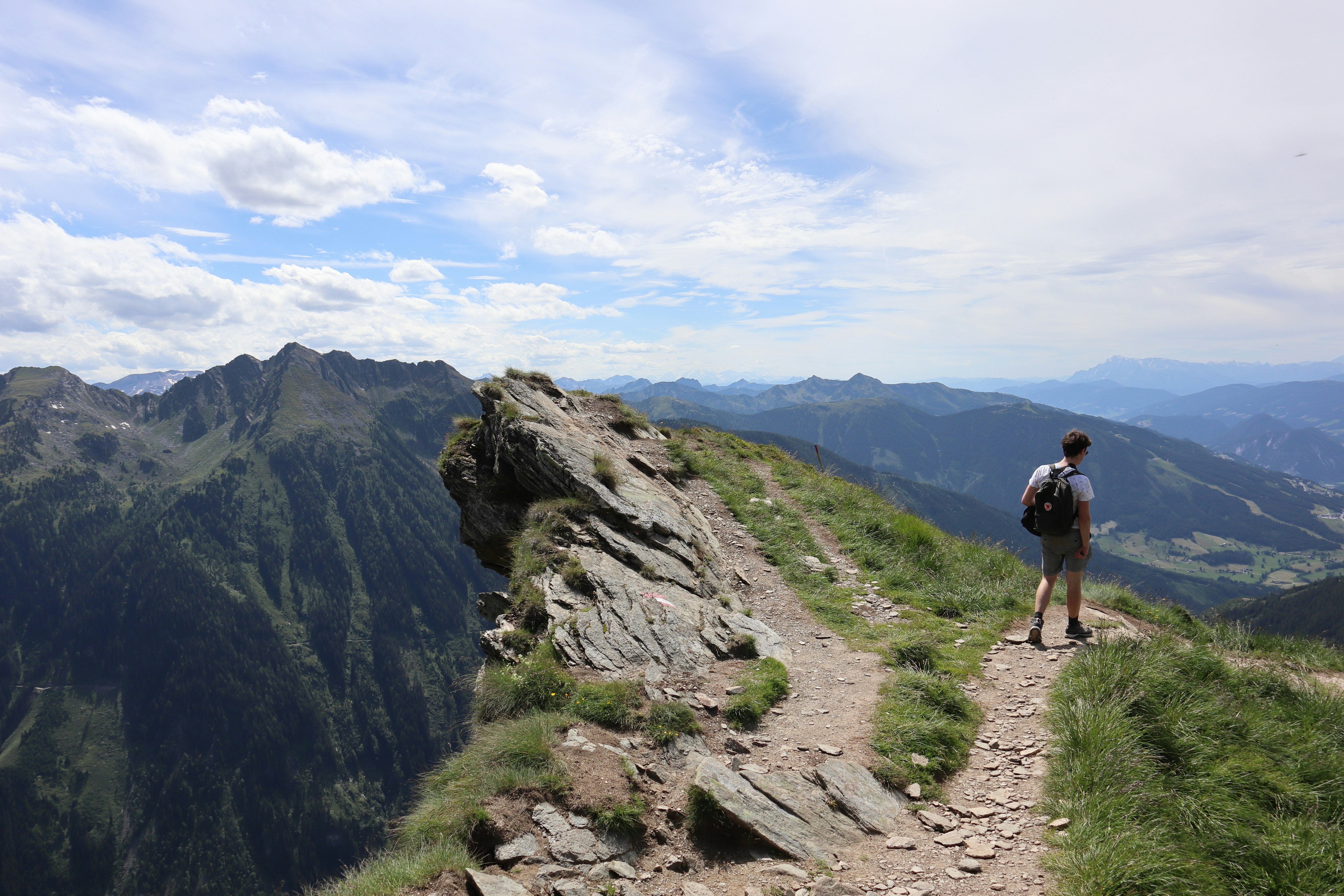 Hiker standing at scenic overlook with mountains in background