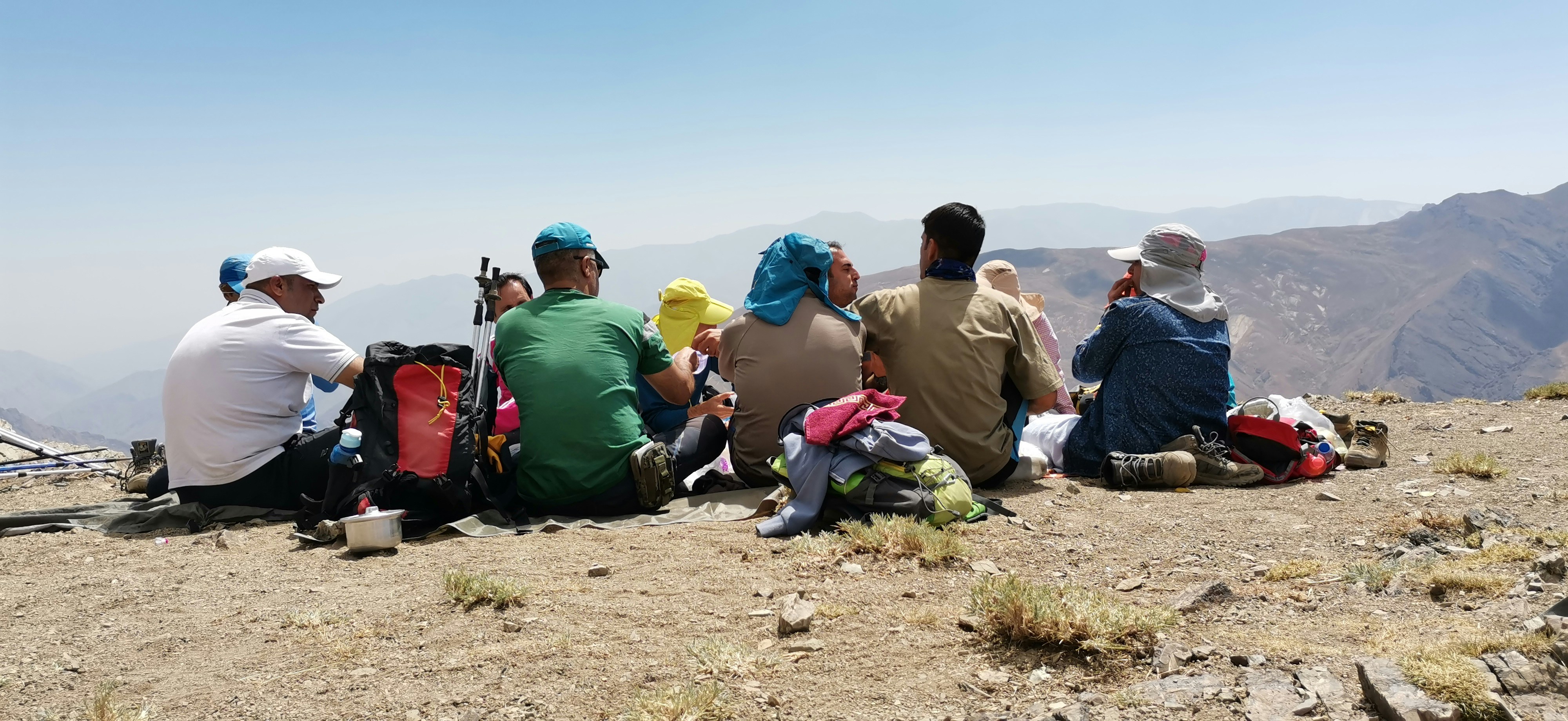 Tour group of hikers taking break at mountain summit with scenic backdrop